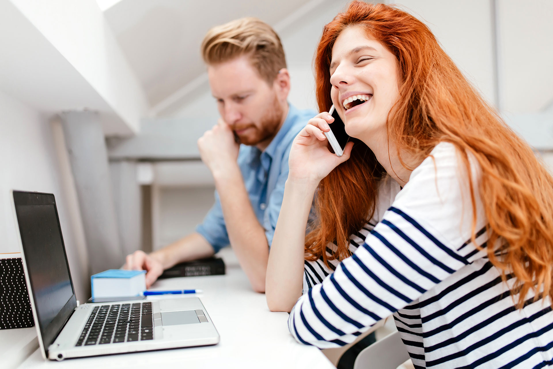 vrouw aan de telefoon met man op de achtergrond
