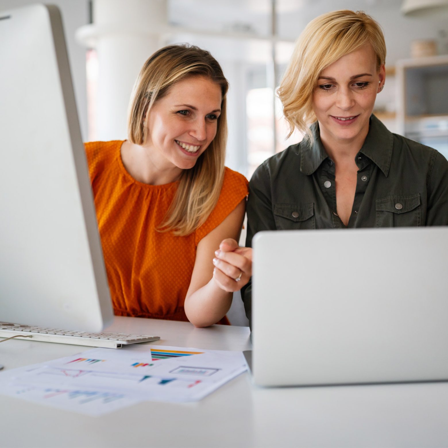 twee vrouwen achter een laptop en een desktop