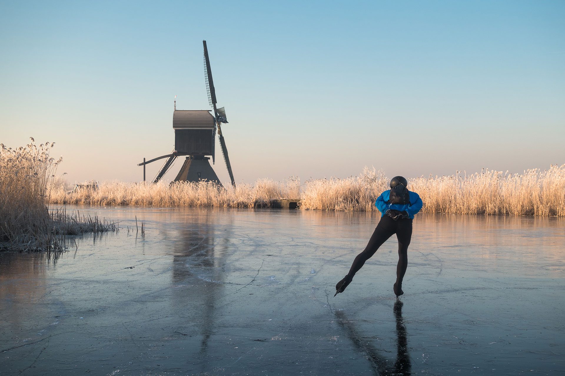winterlandschap met schaatser en molen