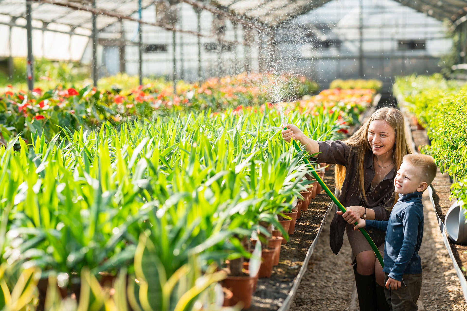 vrouw en kind sproeien in serre